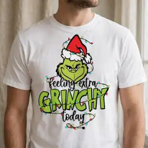 A green character wearing a Santa hat, surrounded by Christmas lights and text. design printed on a plain product mockup