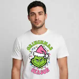 pink grinch bundle grinchmas season svg for christmas crafts A green, furry, grumpy face wearing a pink Santa hat, surrounded by Christmas lights and text. design printed on a plain prod