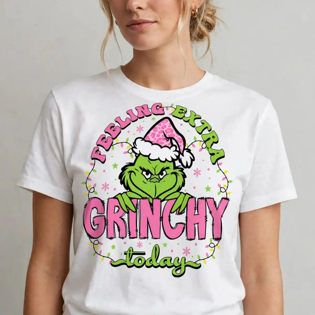 pink grinch bundle: feeling extra grinchy today christmas cut file for t-shirts & mugs a green furry character wearing a pink leopard print Santa hat, with text and Christmas lights design printed on a plain prod
