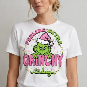 pink grinch bundle: feeling extra grinchy today christmas cut file for t-shirts & mugs a green furry character wearing a pink leopard print Santa hat, with text and Christmas lights design printed on a plain prod